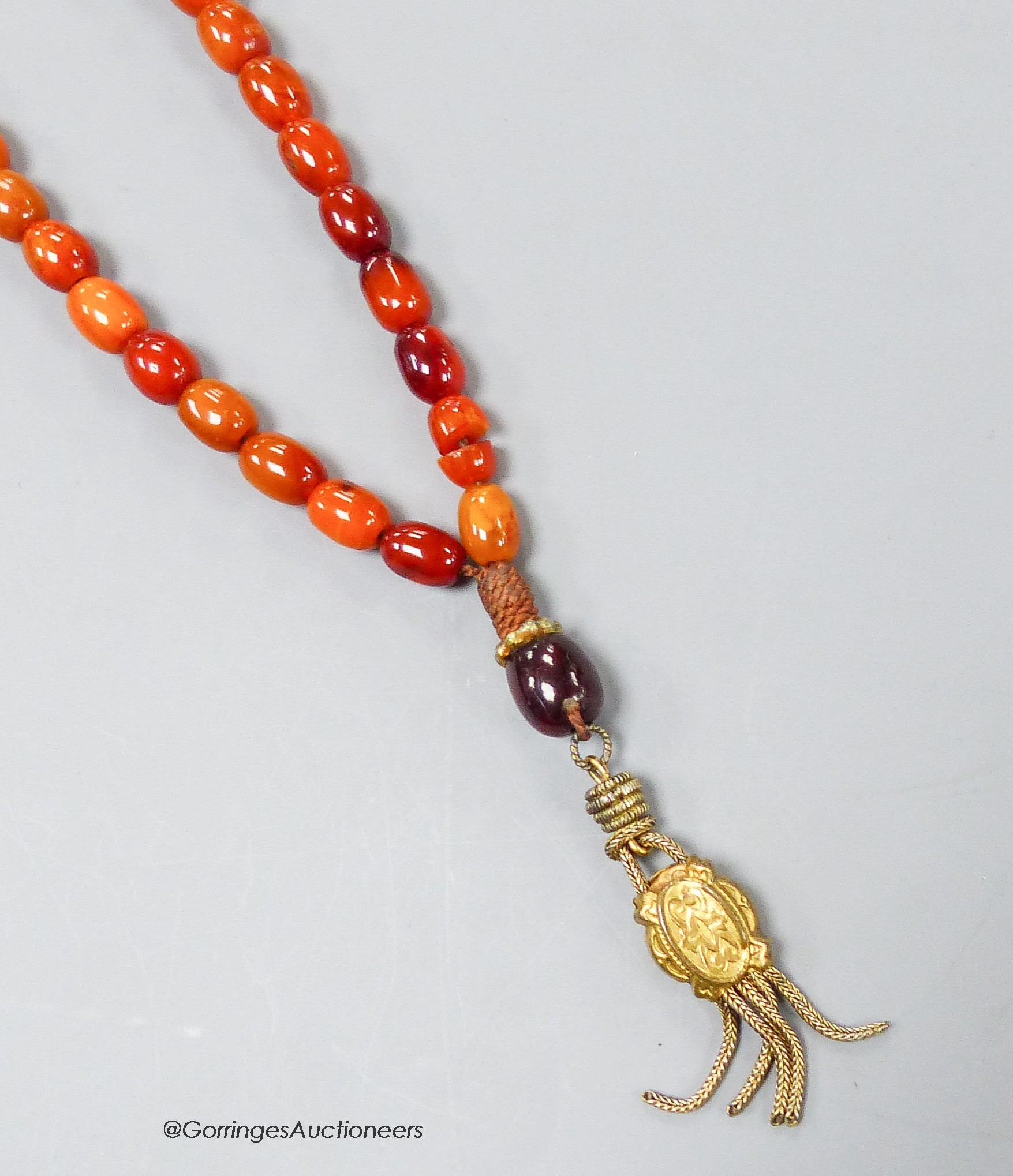 A single strand amber bead necklace, with gilt metal pendant, 36cm, gross weight 12 grams.